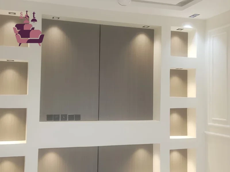 تصميم وتنفيذ وحدة أرفف جدارية فاخرة متكاملة، تتضمن خزائن مدمجة وأرفف مضيئة بتشطيب احترافي راقي.