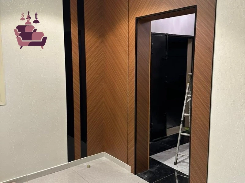 ديكور جداري فاخر يدمج بين ألواح بديل الرخام باللون الأبيض مع عروق رمادية وكسوة خشبية رأسية داكنة، يحتوي على مدفأة كهربائية مدمجة وشاشة تلفاز مثبتة، منفذ بدقة عالية في صالة مودرن بخميس مشيط حي الرصراص.
